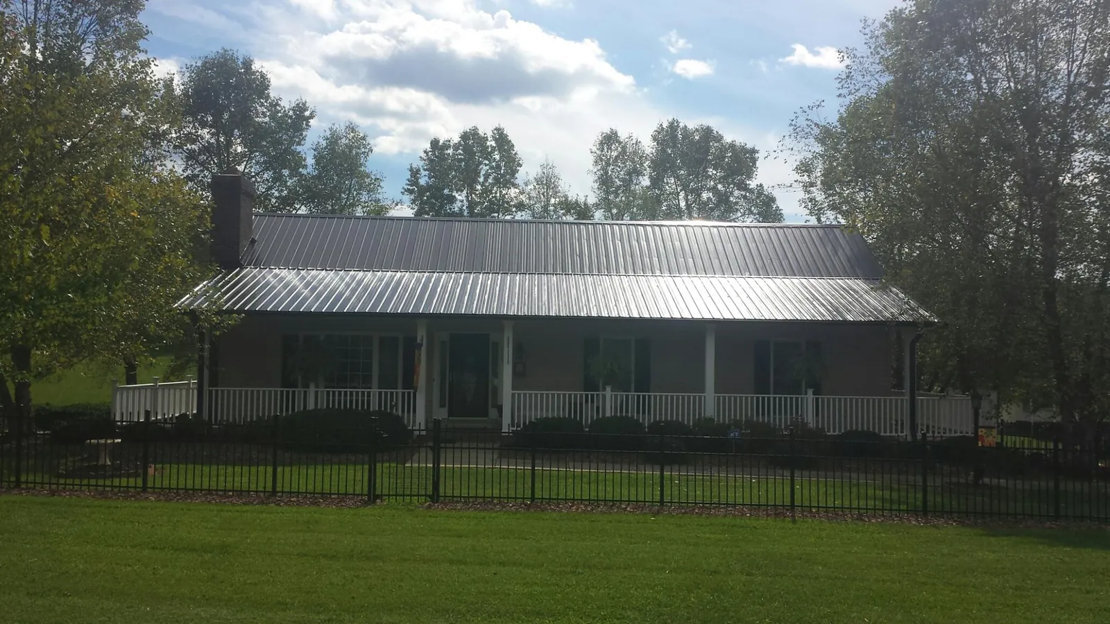 Gray metal roof on a brick ranch with a full width front porch — Gutter Guard Installation work by our crew in Misenheimer