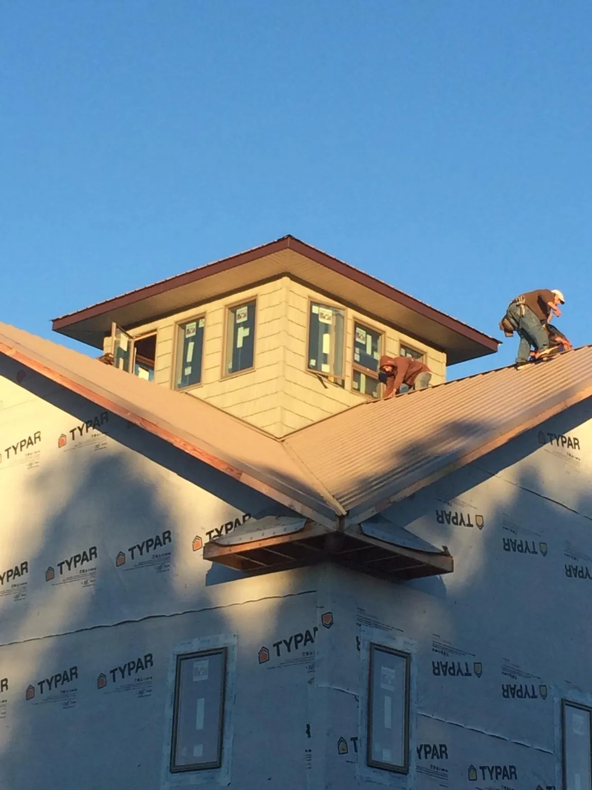 Roofers working around a rooftop cupola on a new metal roof at sunset — Roof Waterproofing in Misenheimer by Roofing Brothers